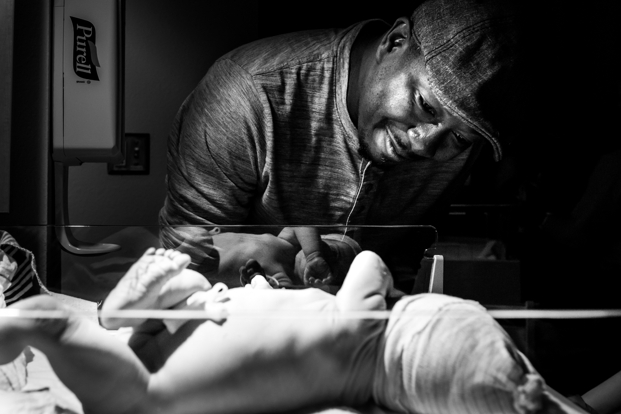 Lawren Rose Photography, a DFW Birth Photographer, captures a new dad gazing at his newborn baby girl under the heat lamp at the Frisco Centennial hospital