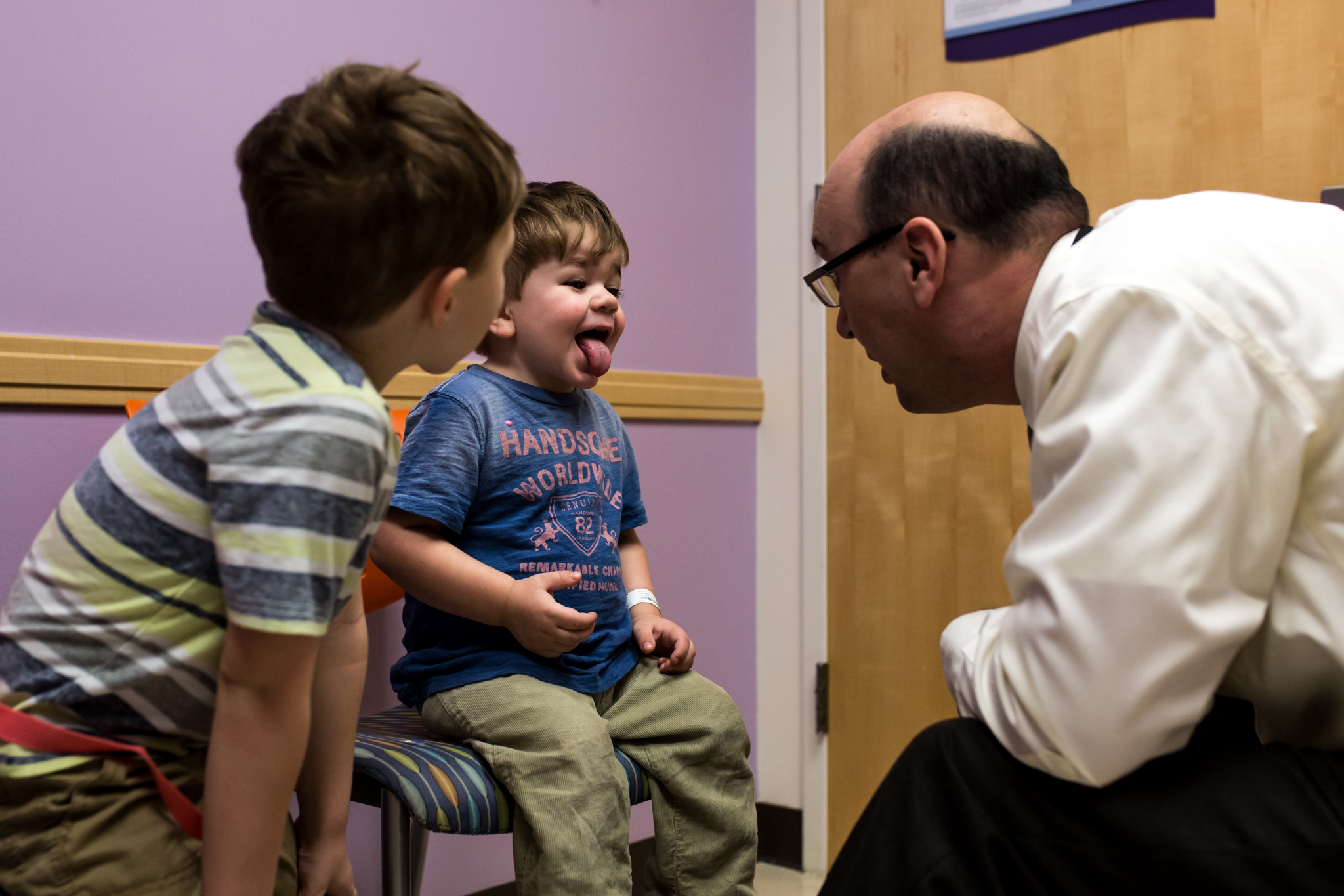 little boy sticking his tongue out for the doctor to look in his throat