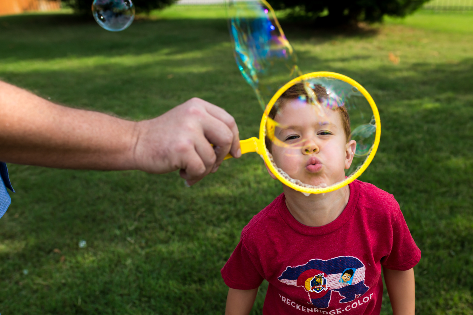 Maternity Photographer Lawren Rose Photography takes a photo of a red headed boys face while he is blowing a giant bubble in McKinney Texas