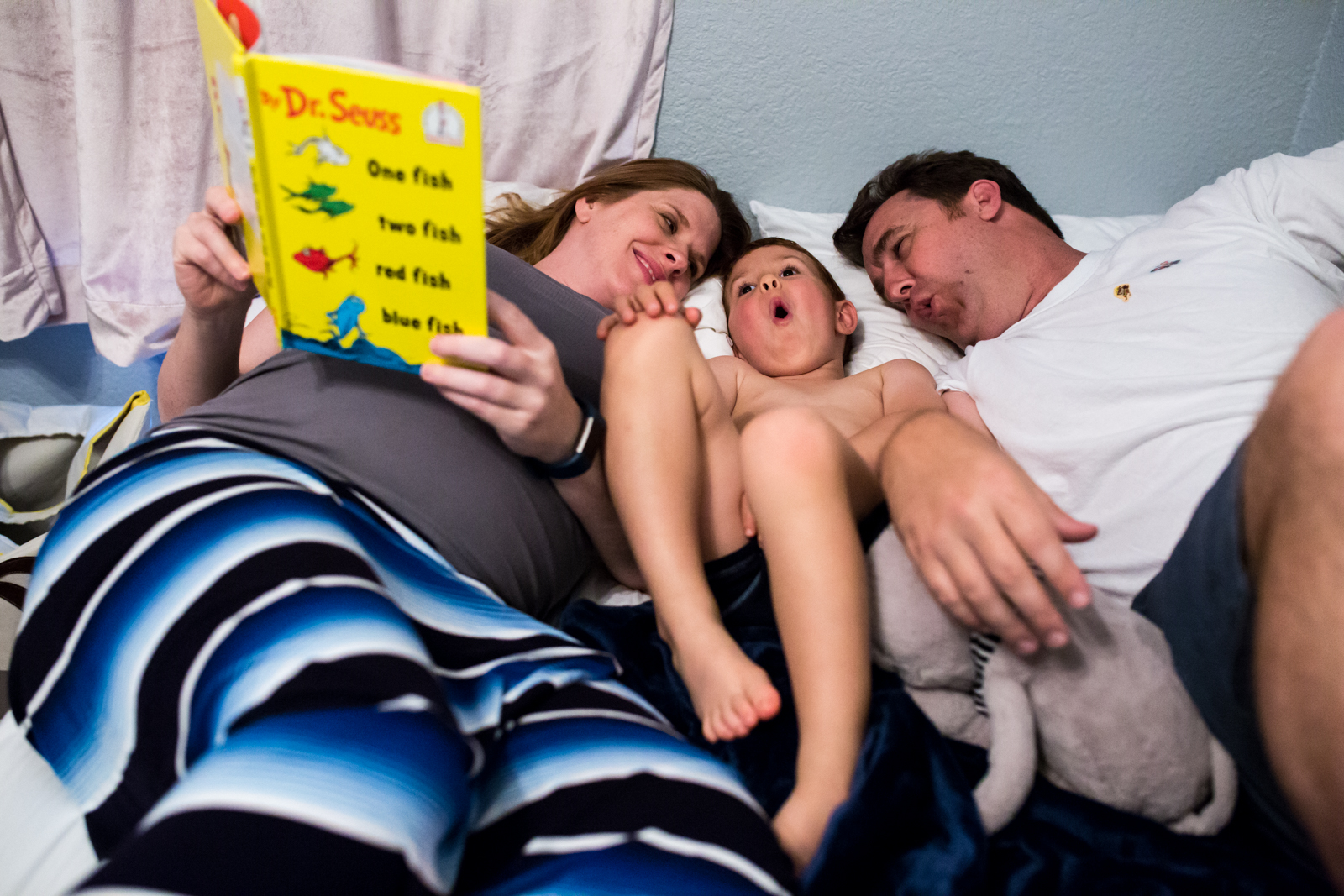 Maternity Photographer Lawren Rose Photography takes a photo of a family acting out a dr seuss book laying in bed in mckinney texas