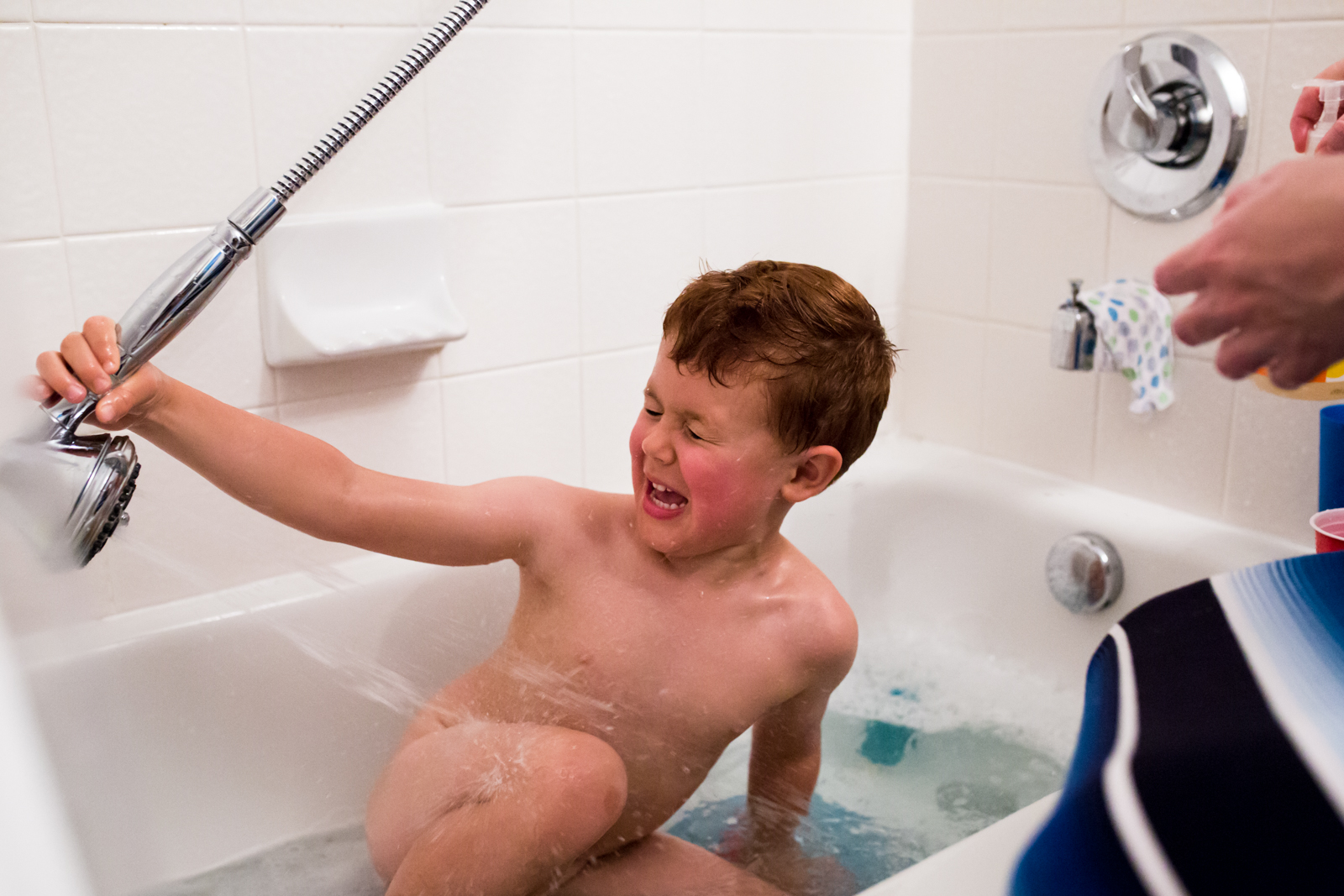 Maternity Photographer Captures a funny moment of a 4 year old boy accidently spraying himself with water in the bath tub in McKinney Texas, Lawren Rose Photography