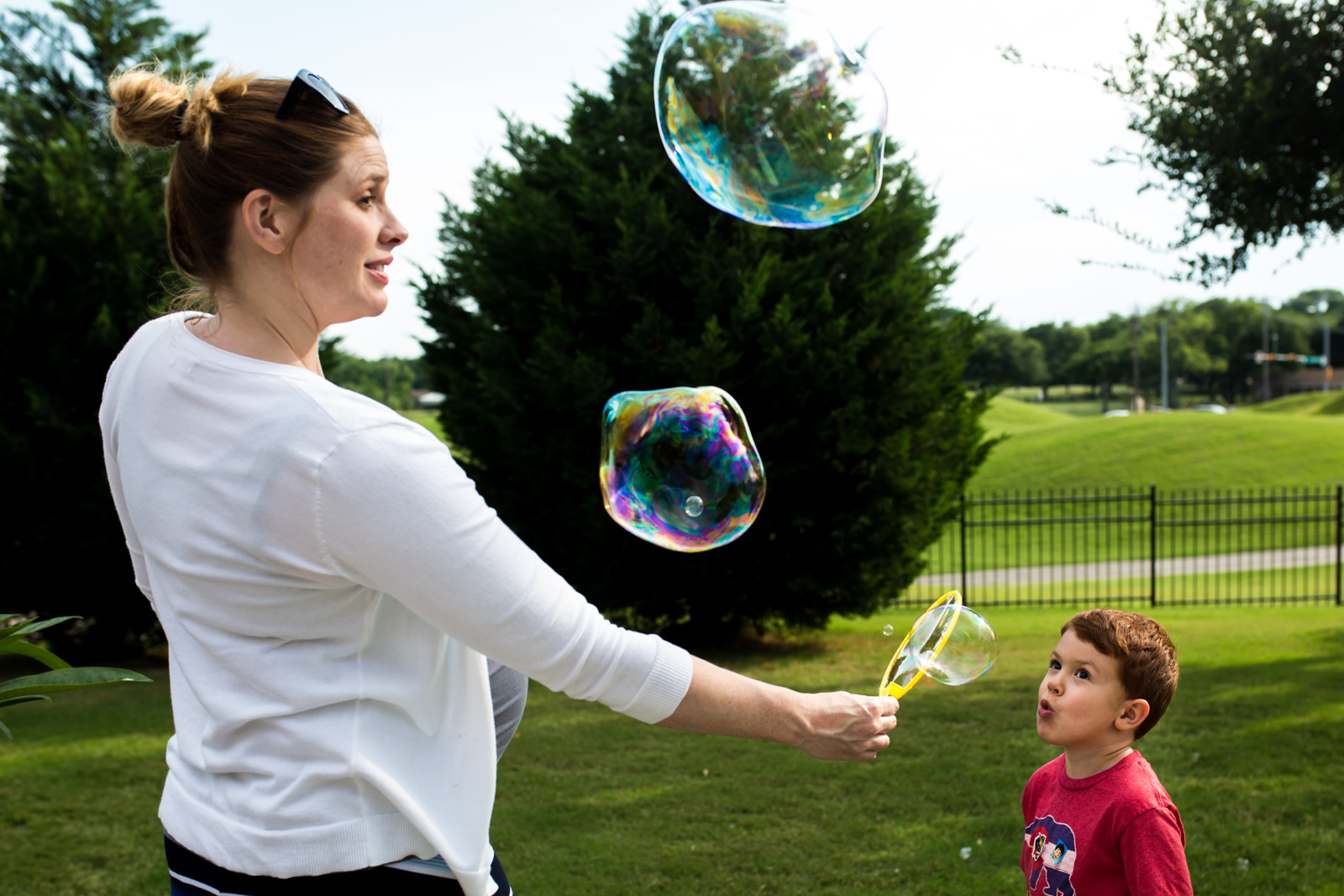 Lawren Rose Photography takes a unique photograph of a pregnant Mom holding a bubble wand while her 4 year old son blows and looks up at the giant bubbles he is creating in McKinney Texas