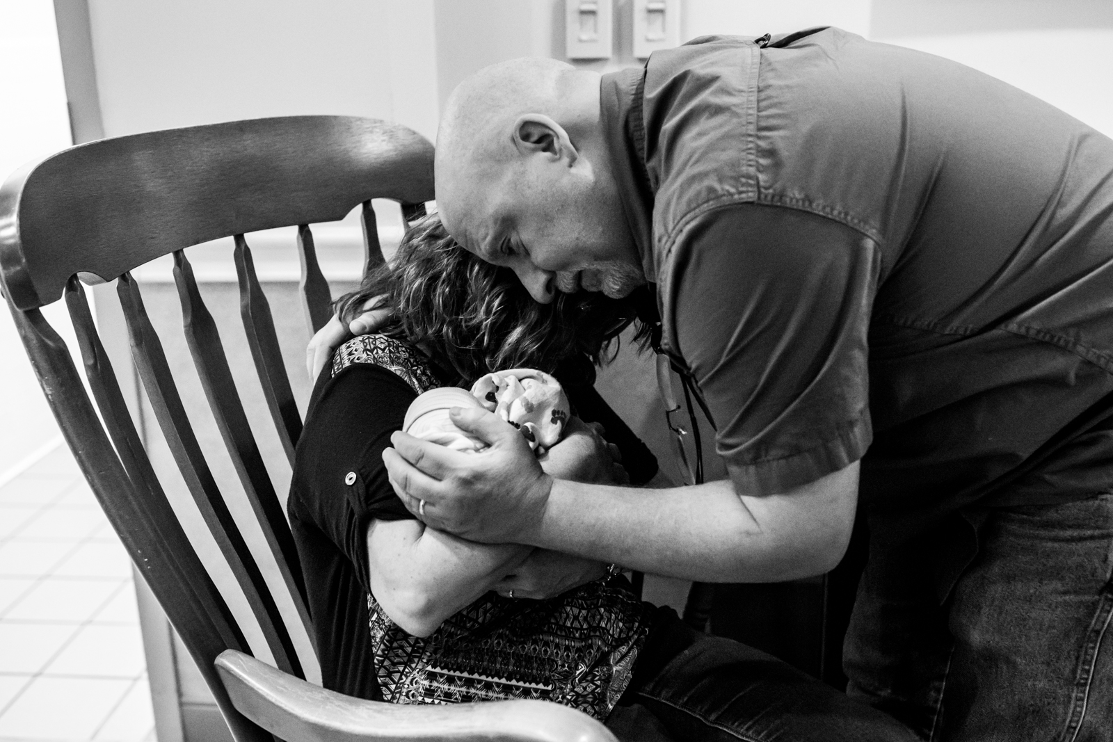 grandparents hold each other as they carry their grand baby