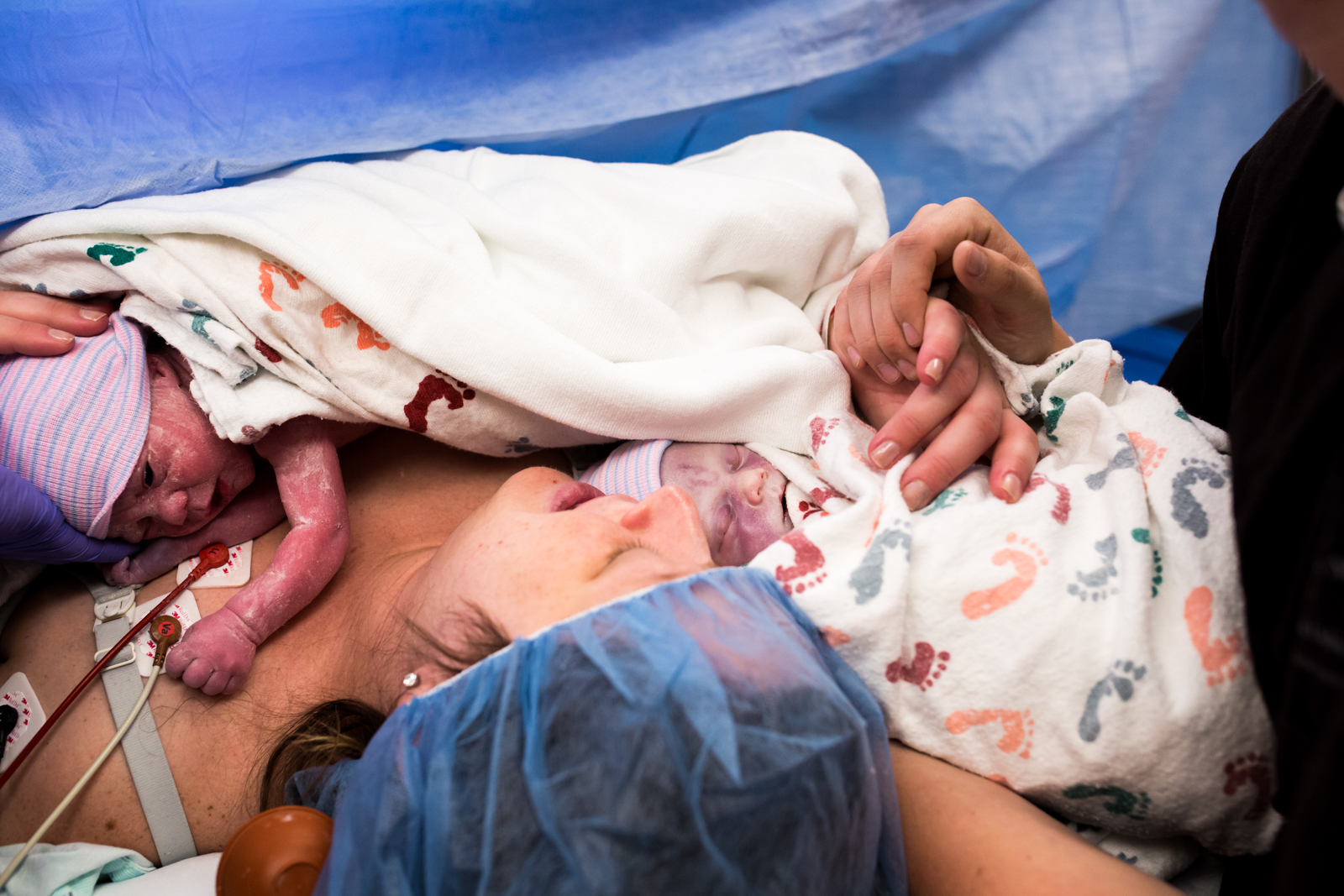 husband and wife hold hands as they hold their newborn babies