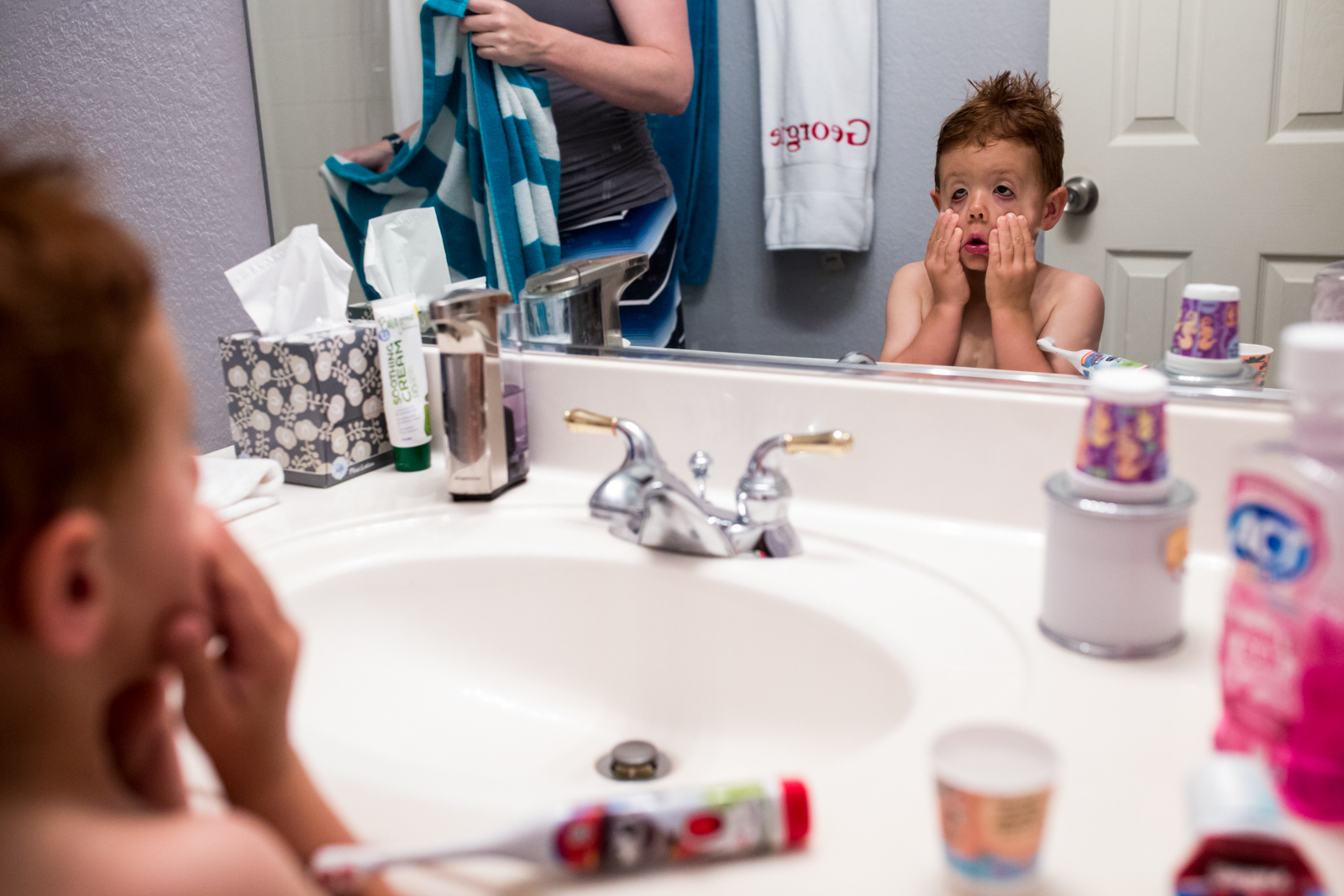 Lawren Rose Photography takes a funny photo during a maternity session of a little boy making goofy faces at himself in the bathroom mirror in mckinney texas