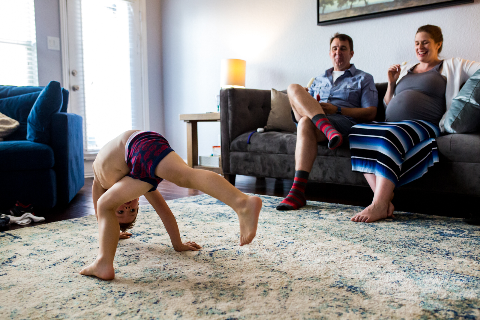 Maternity photographer Lawren Rose Photography captures a funny moment of a 4 year old boy throwing himself all over the living room dancing while his mom and dad sit back and laugh in McKinney Texas