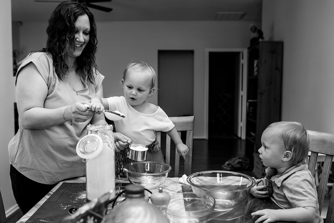 Lawren Rose Photography takes a photograph of a Mother baking and measuring out flour with the help of her twins in a McKinney, Texas in-home family session