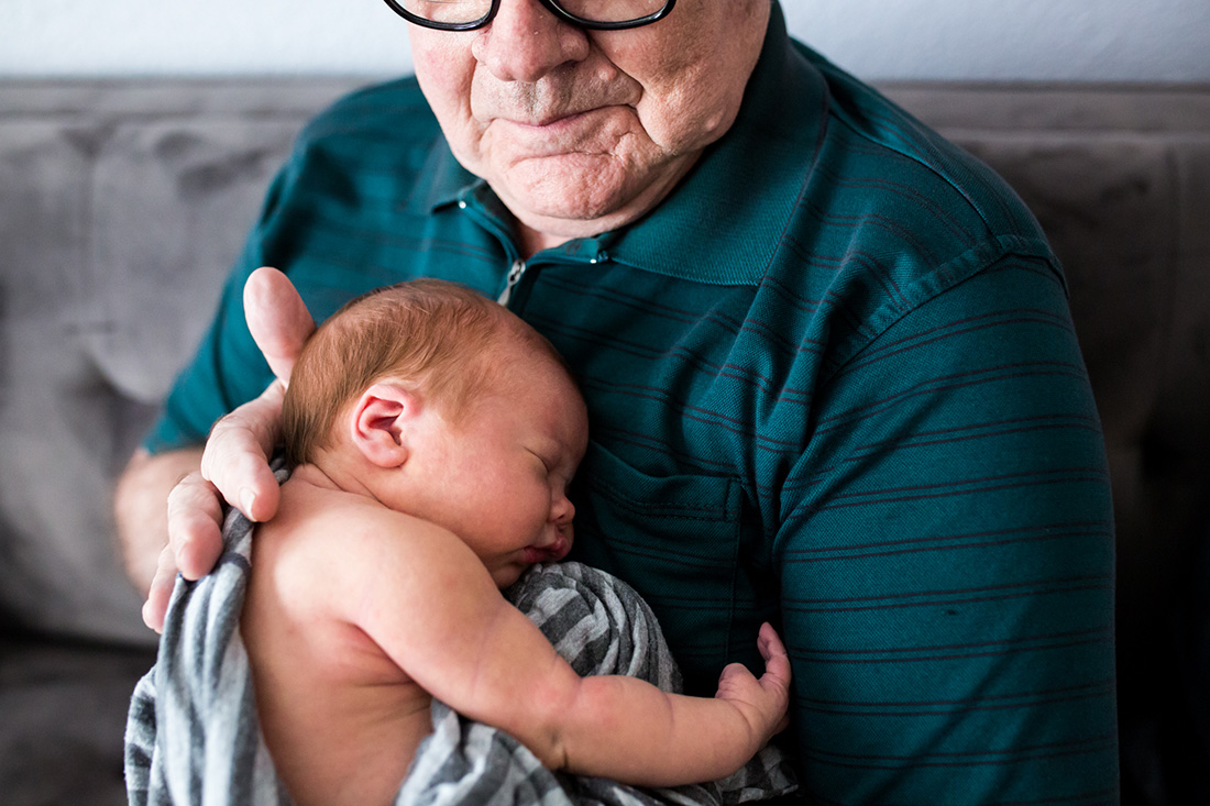 Lawren Rose Photography takes a picture of a grandpa holding his newborn granddaughter in McKinney Texas