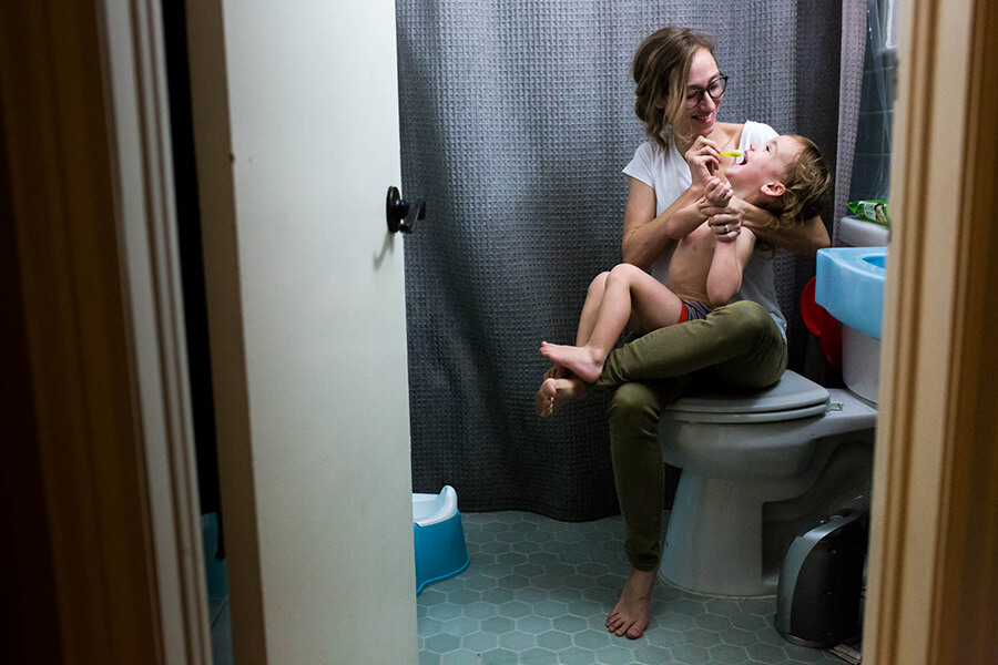 Lawren Rose Photography, a dallas family photojournalist, takes a photograph of a Mom trying to brush her wild child's teeth