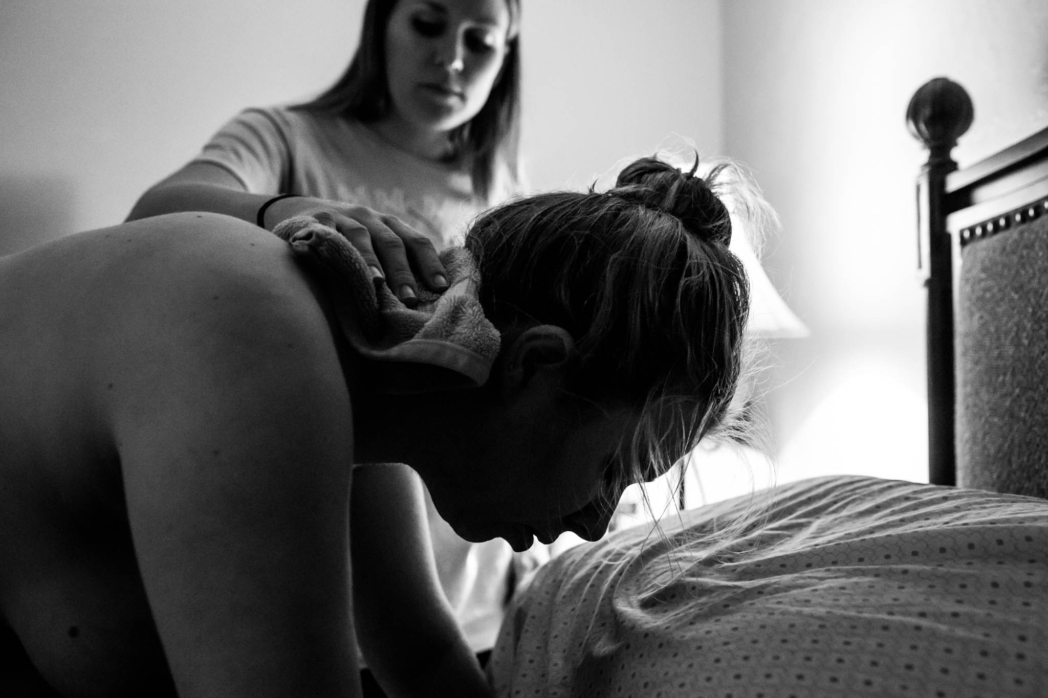 Lawren Rose Photography takes a picture during a home birth in Richardson, Texas of a doula helping a laboring mom