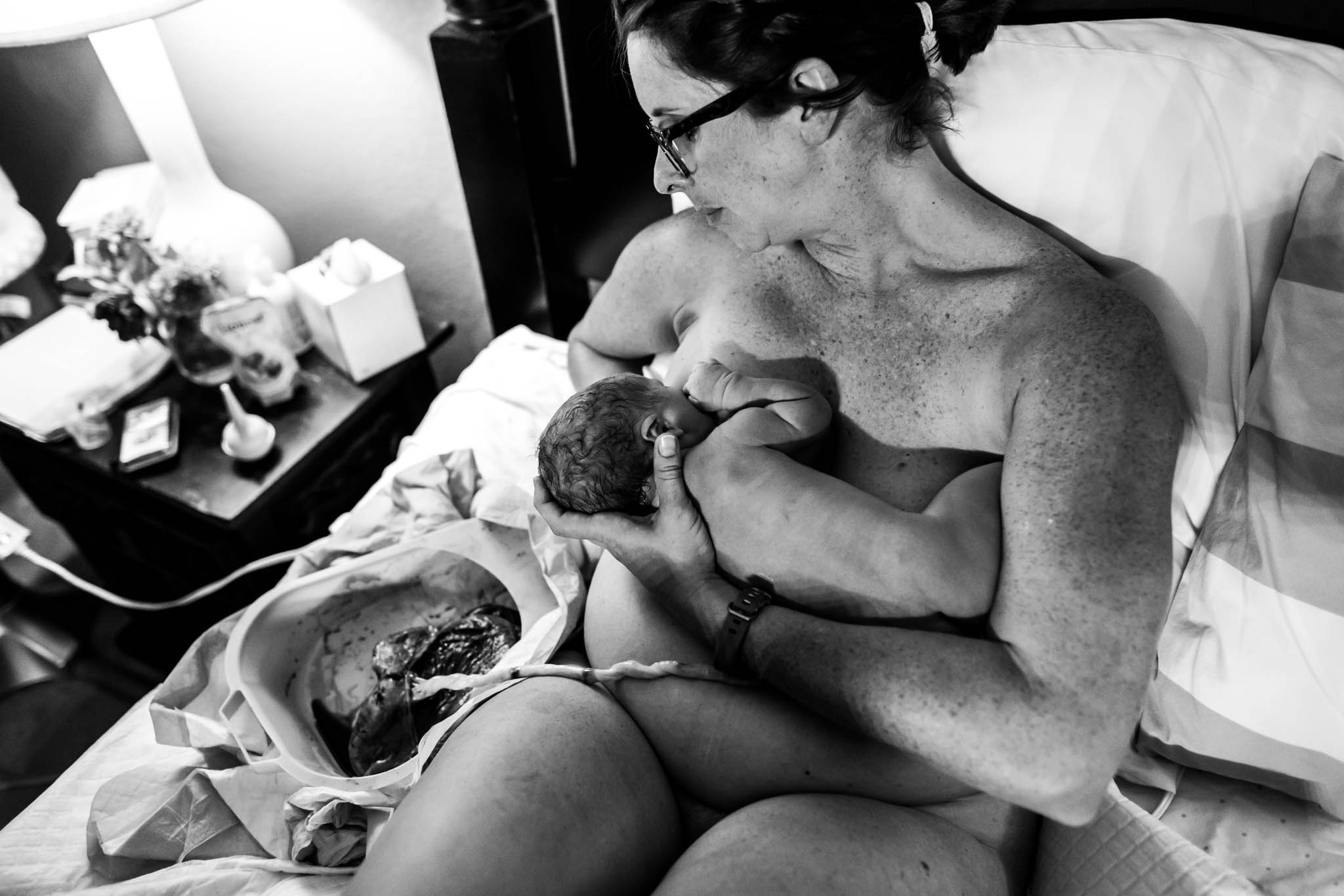 During a Denton, Texas home birth, Lawren Rose Photography takes a photograph from above as a new mom was breastfeeding her baby for the first time, with placenta still attached and sitting nearby