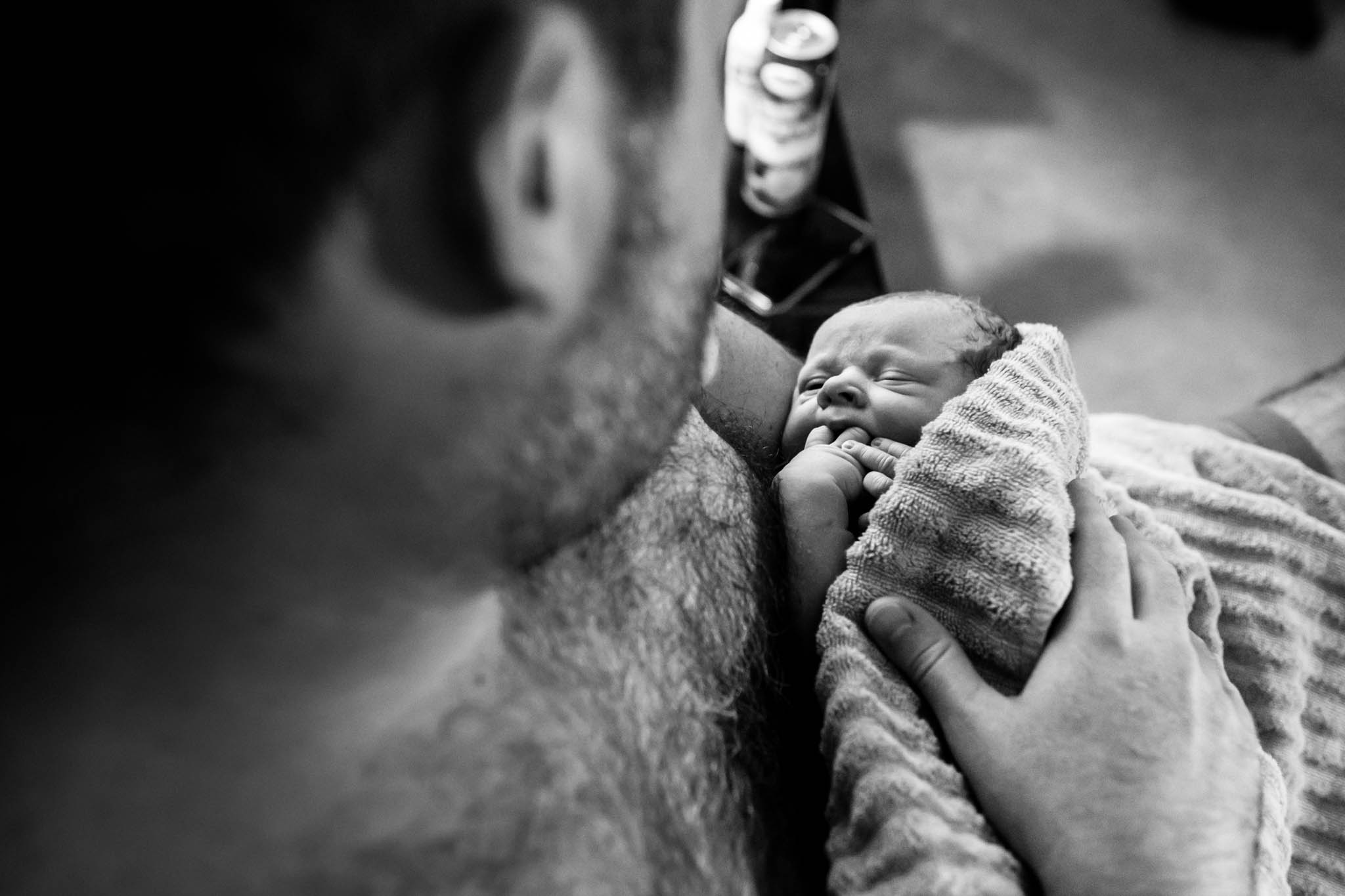 right after a home birth in Denton, Texas, Lawren Rose Photography takes a picture from above of Dad holding his baby boy for the first time