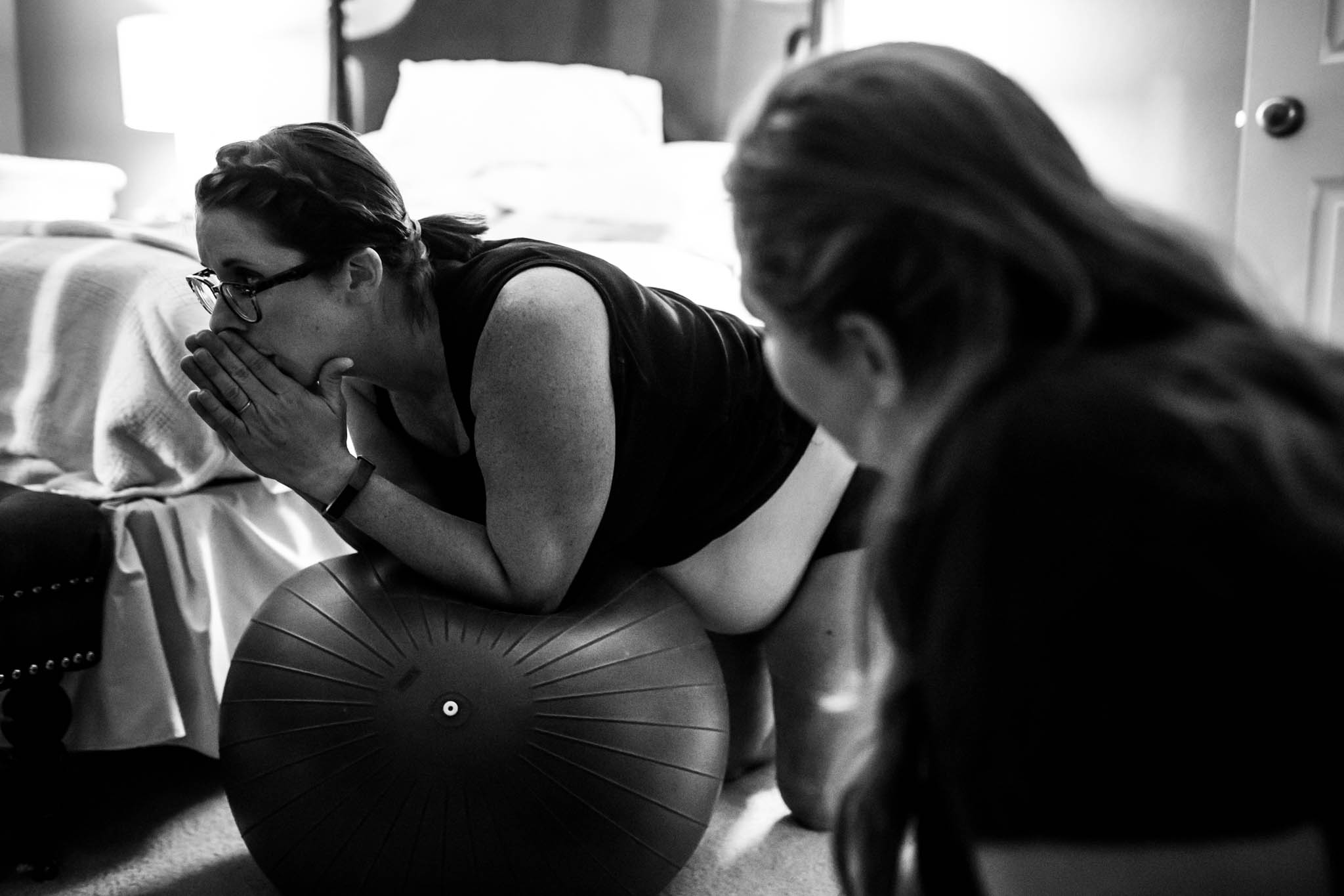 Lawren Rose Photography takes a photograph of a doula watching her laboring client during a home birth in Denton, Texas