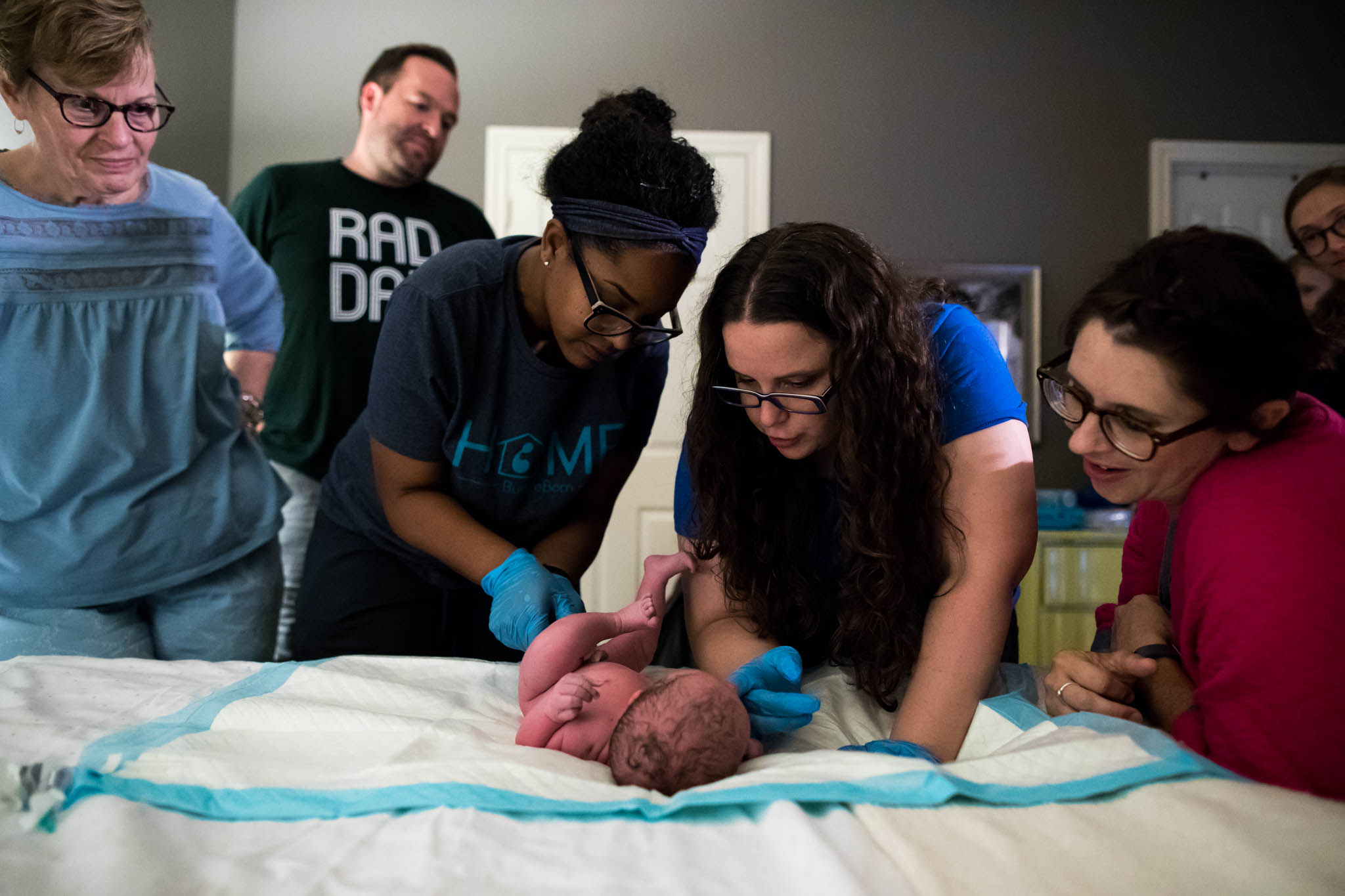 An image taken by Lawren Rose Photography during a Denton, texas home birth as the birth team do the newborn exam