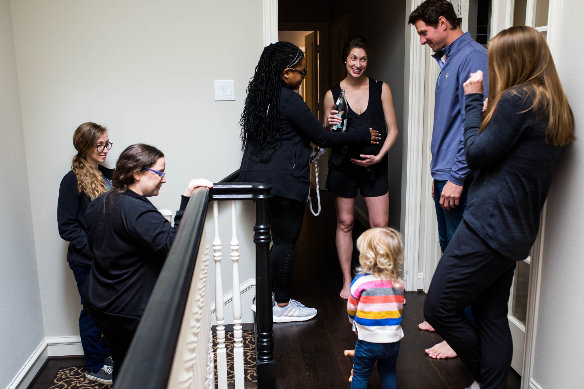 Lawren Rose Photography, a dallas birth photographer, takes a picture of a mom surrounded by her supportive birth team during active labor